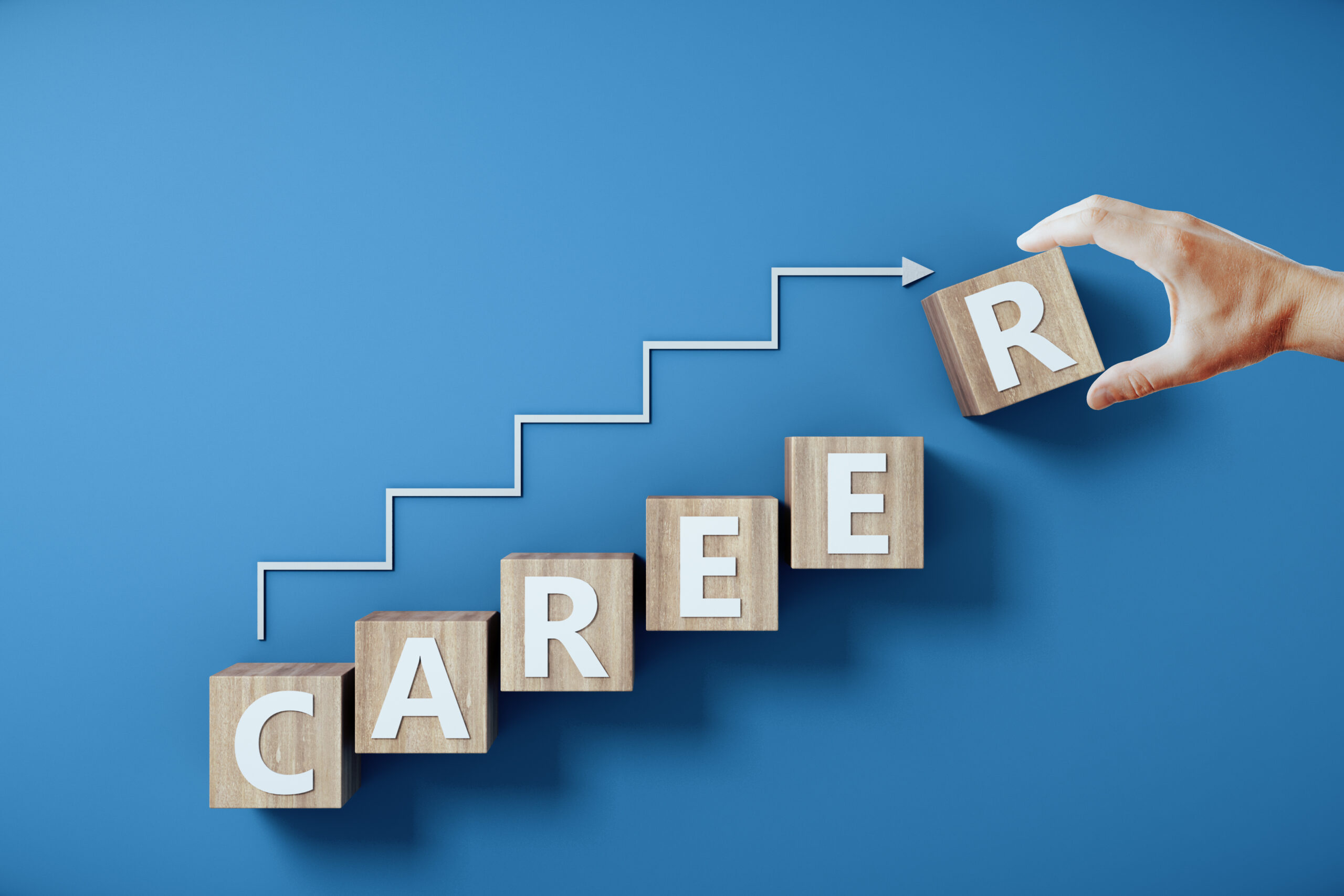 A hand places a wooden block with the letter "R" on top of blocks spelling the word "CAREER," representing career milestones.